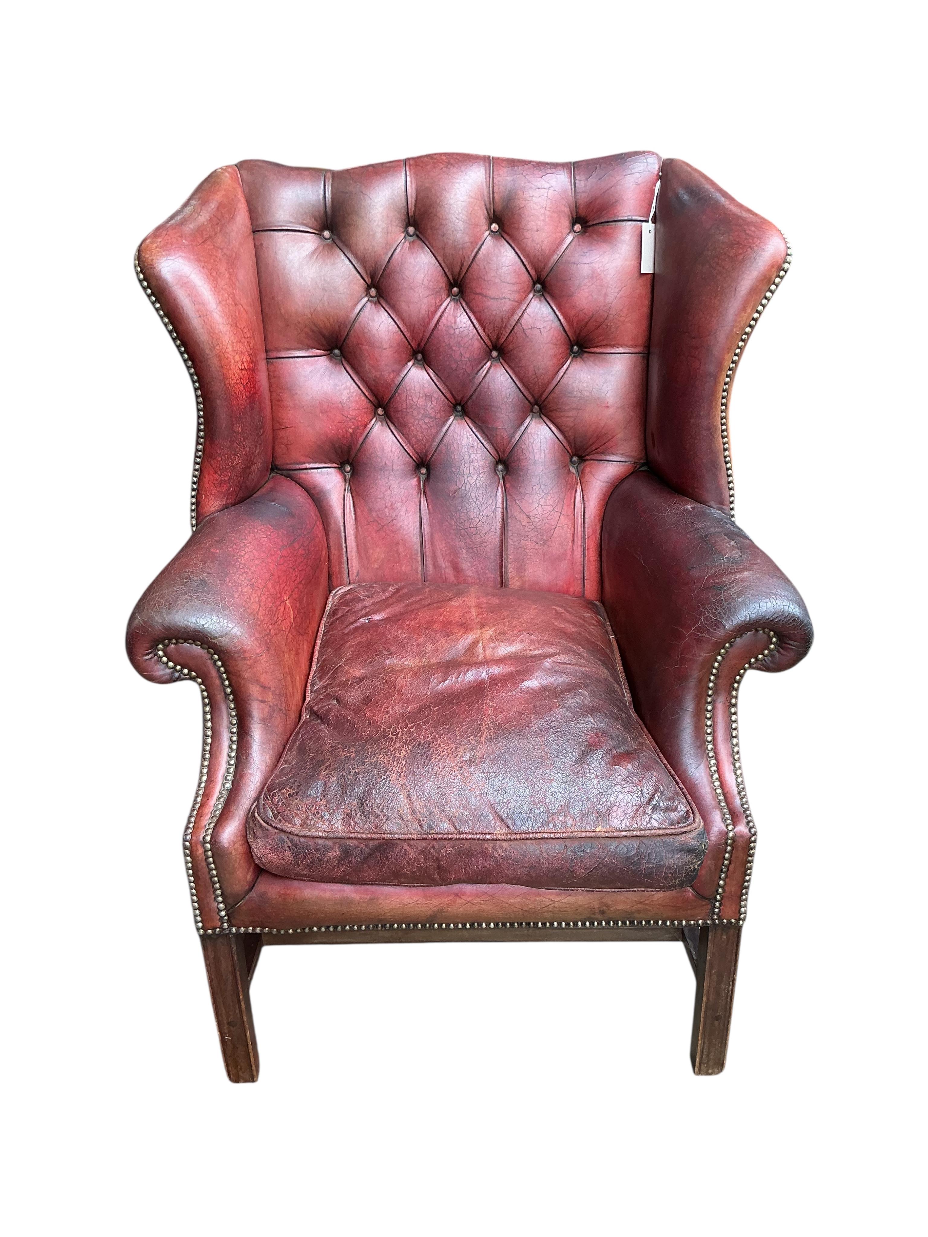 A George III style buttoned burgundy leather wing armchair